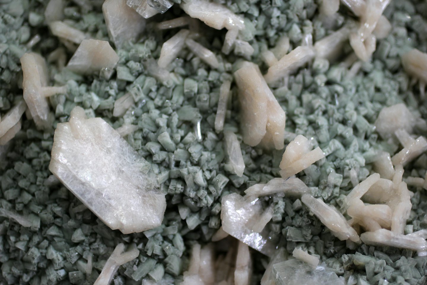 Light green and white mineral crystals form an intricate textured surface.